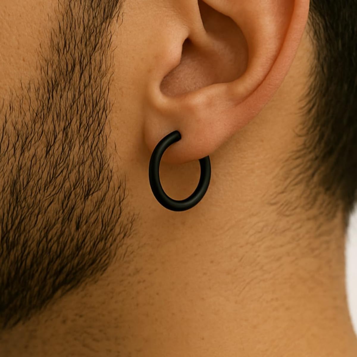 Close-up of a man wearing a black hoop earring on a neutral background