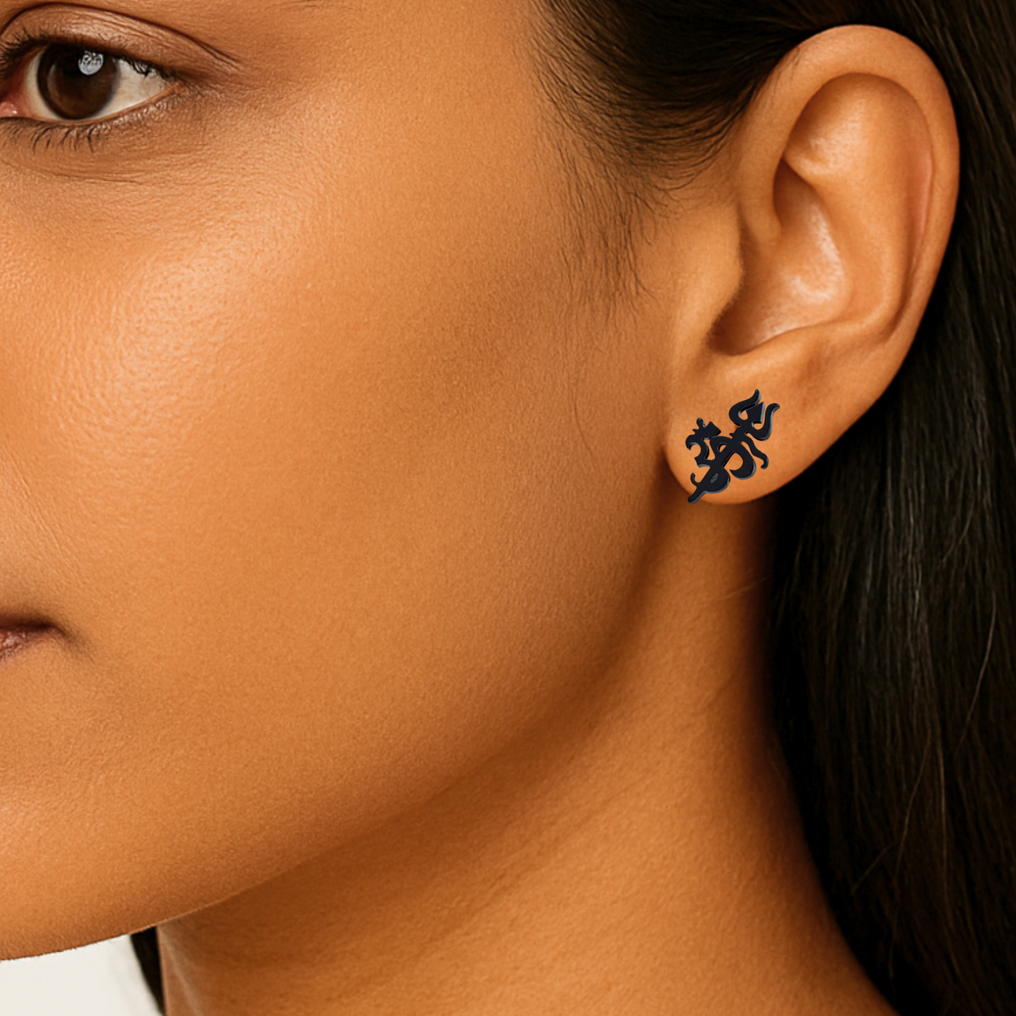 Close-up of an ear wearing a black om stud earring with a blurred background