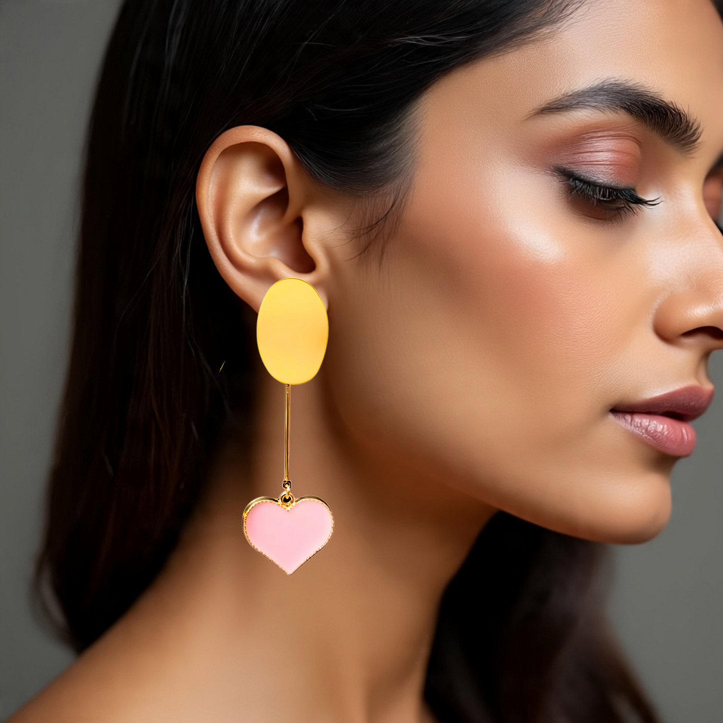 Close-up of a woman wearing a yellow and pink heart-shaped earring against a neutral background