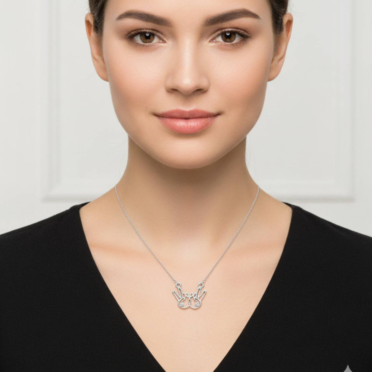 Woman wearing a silver necklace with a pendant on a plain background