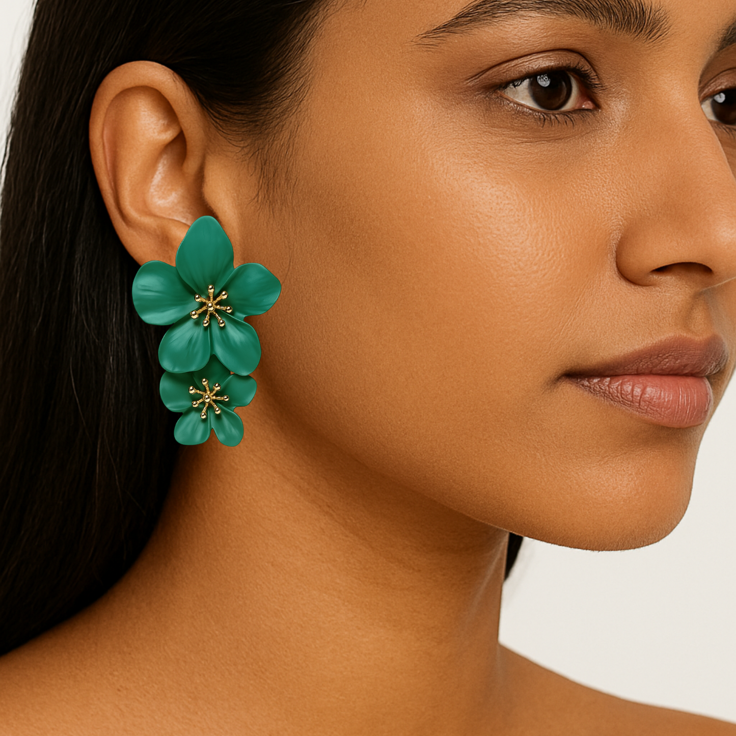 Close-up of a woman wearing green floral earrings with a neutral background