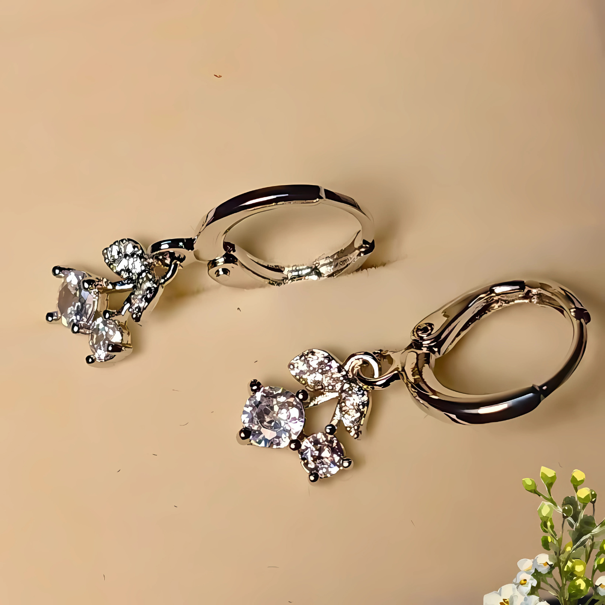 Pair of silver hoop earrings with heart-shaped gemstones on a beige background.