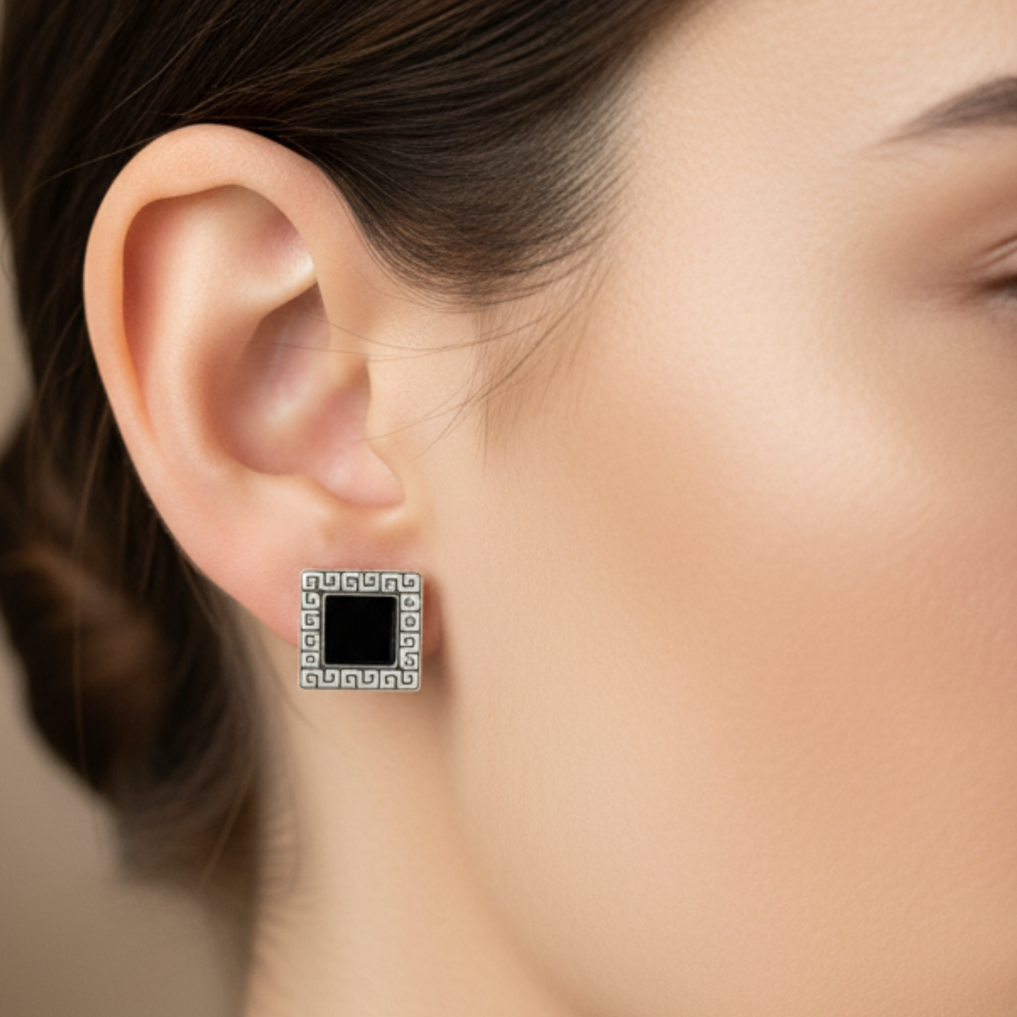 Square earring with black center worn by a person