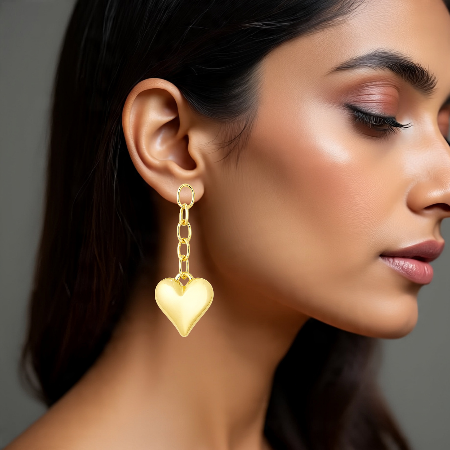 Close-up of a woman wearing a gold heart-shaped earring against a neutral background