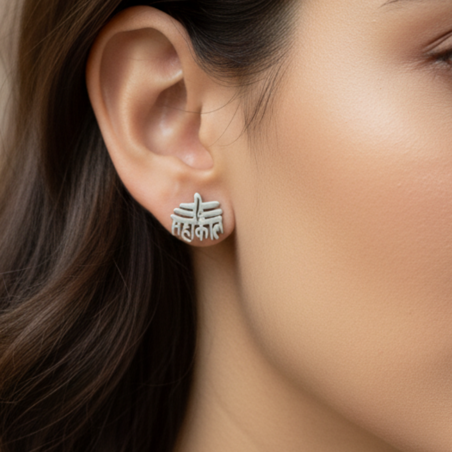 Close-up of an ear wearing a silver earring with intricate design