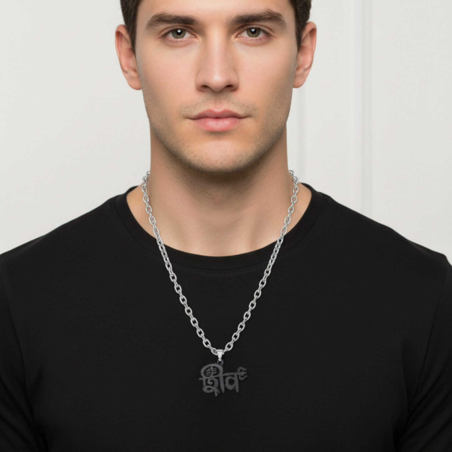 Man wearing a silver necklace with a black shirt against a white background