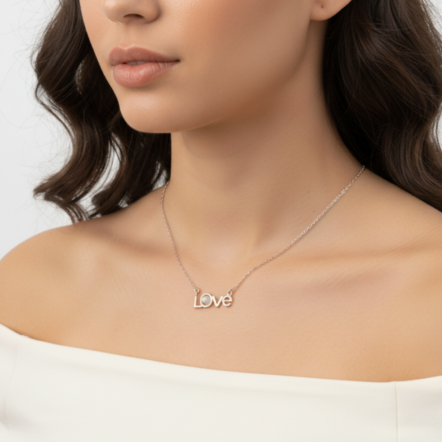 Necklace with 'love' pendant worn by a model on a plain background