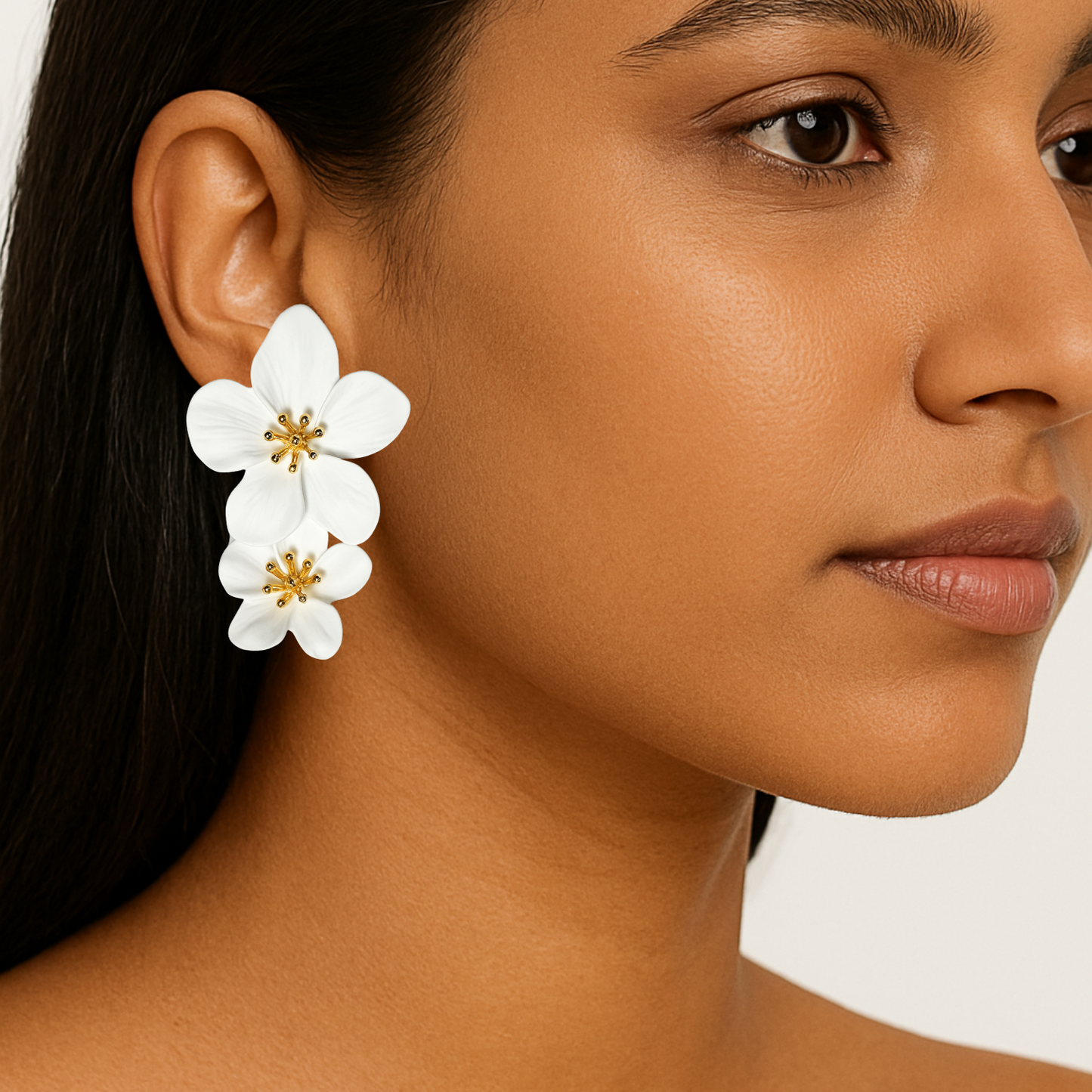 Close-up of a woman wearing white floral earrings with gold centers.