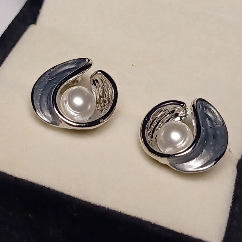 Pair of silver earrings with pearl centers on a white cushion