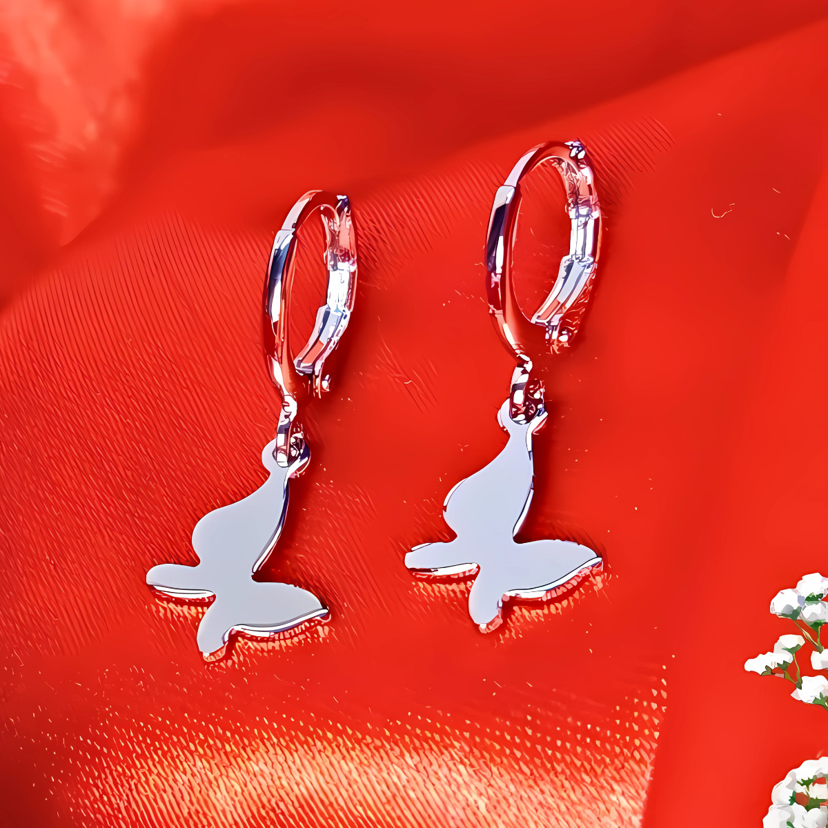 Silver hoop earrings with bunny charms on a red fabric background