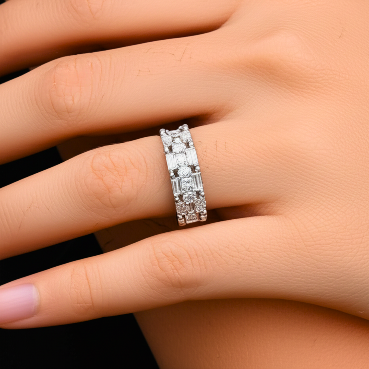 Silver ring with diamonds on a person's finger against a neutral background