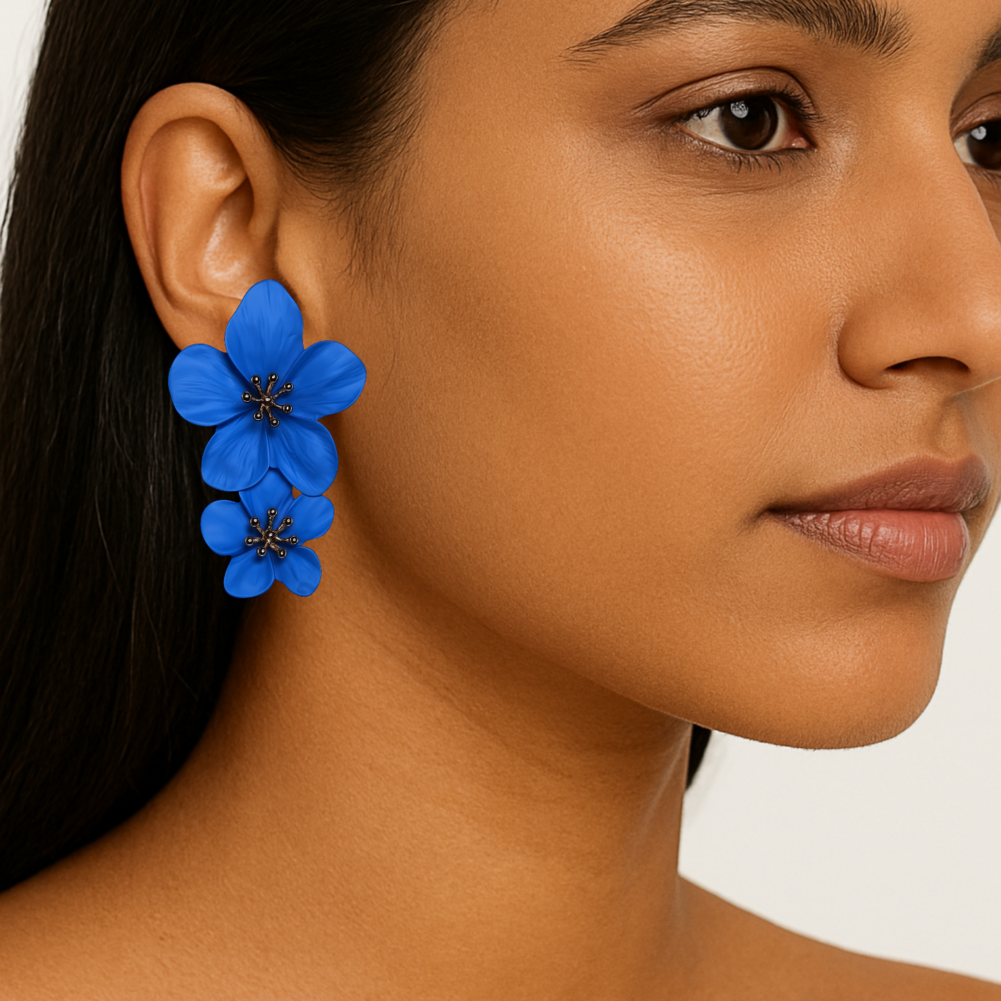 Close-up of a woman wearing blue floral earrings with a neutral background