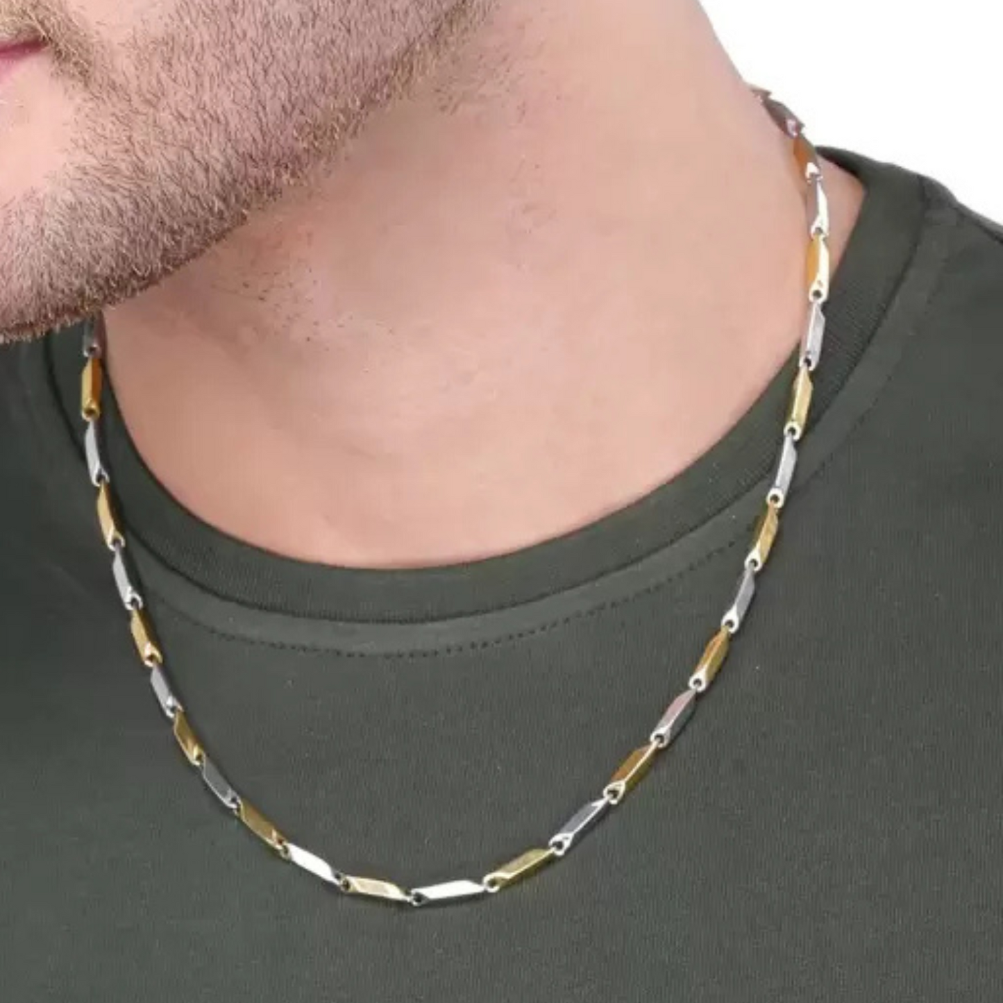 Man wearing a two-tone gold and silver chain necklace on a plain background