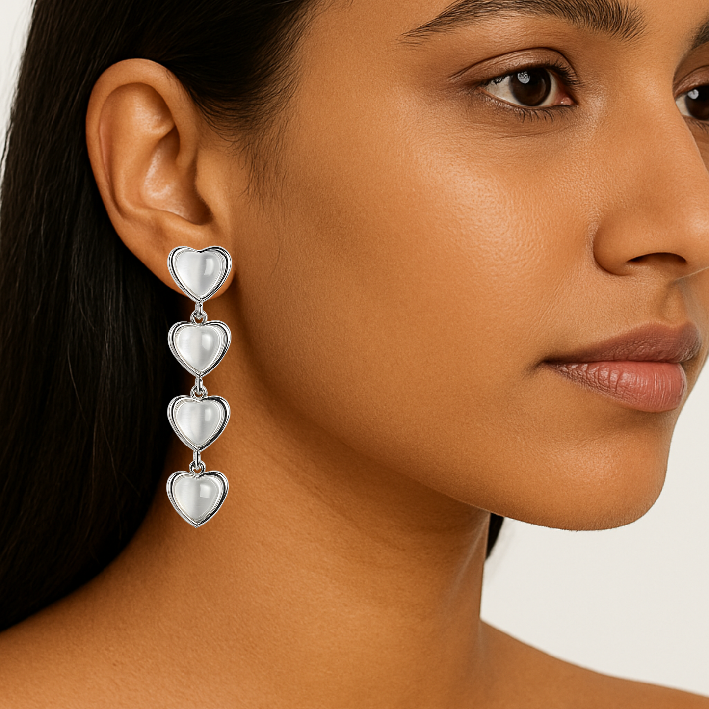 Close-up of a woman wearing a silver heart-shaped earring on a plain background