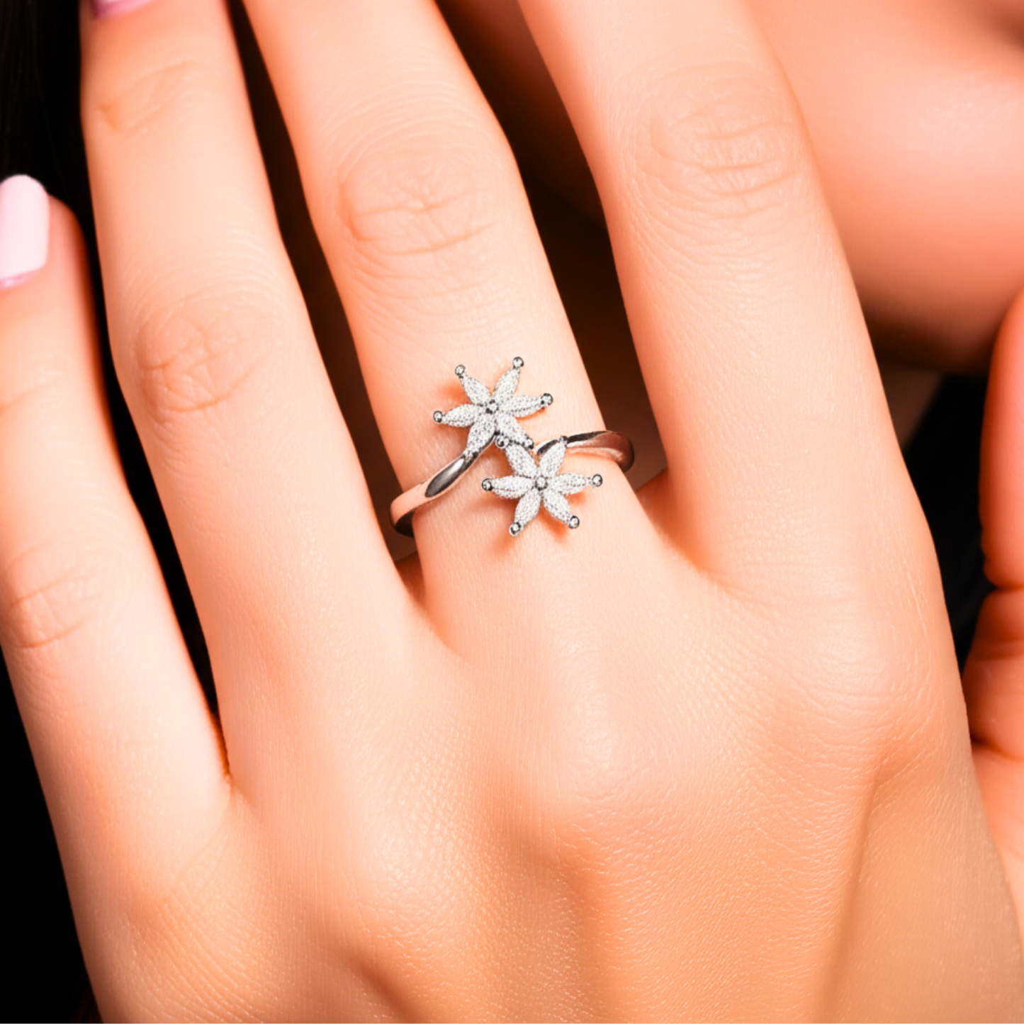 Silver star-shaped ring on a person's finger against a neutral background