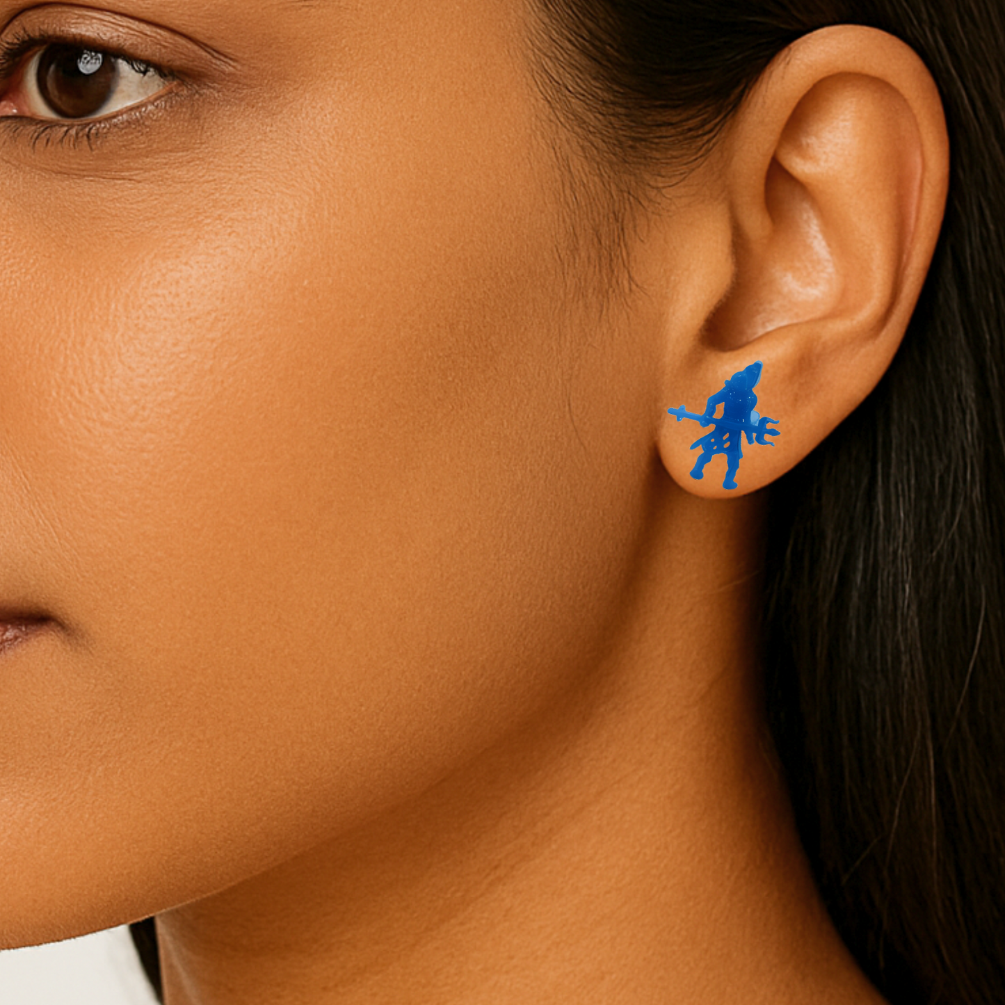 Close-up of a person wearing a blue earring with a shiva design.