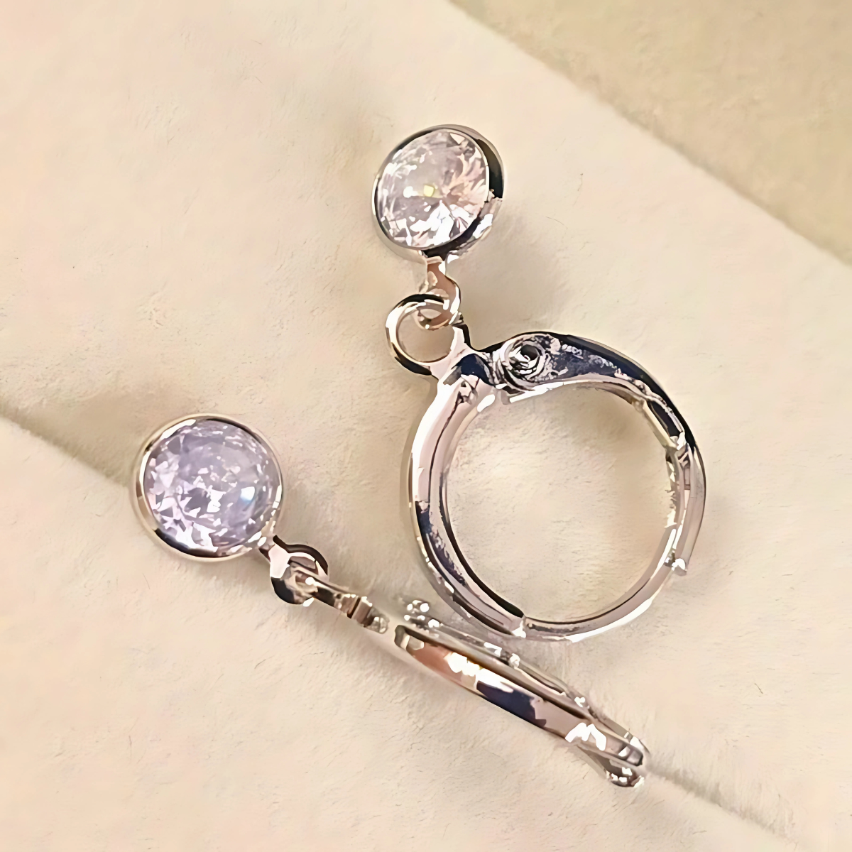 Silver hoop earrings with round gemstones on a beige background