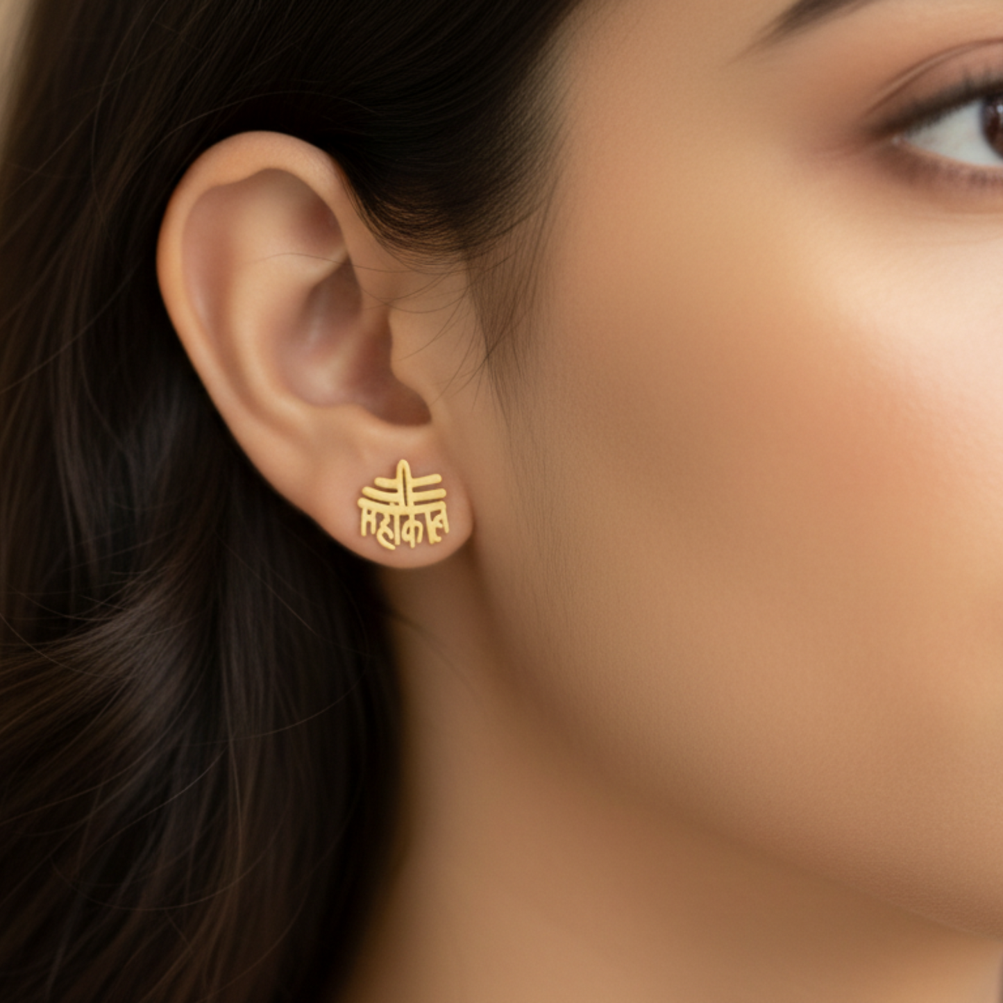 Gold earring worn by a person with blurred background
