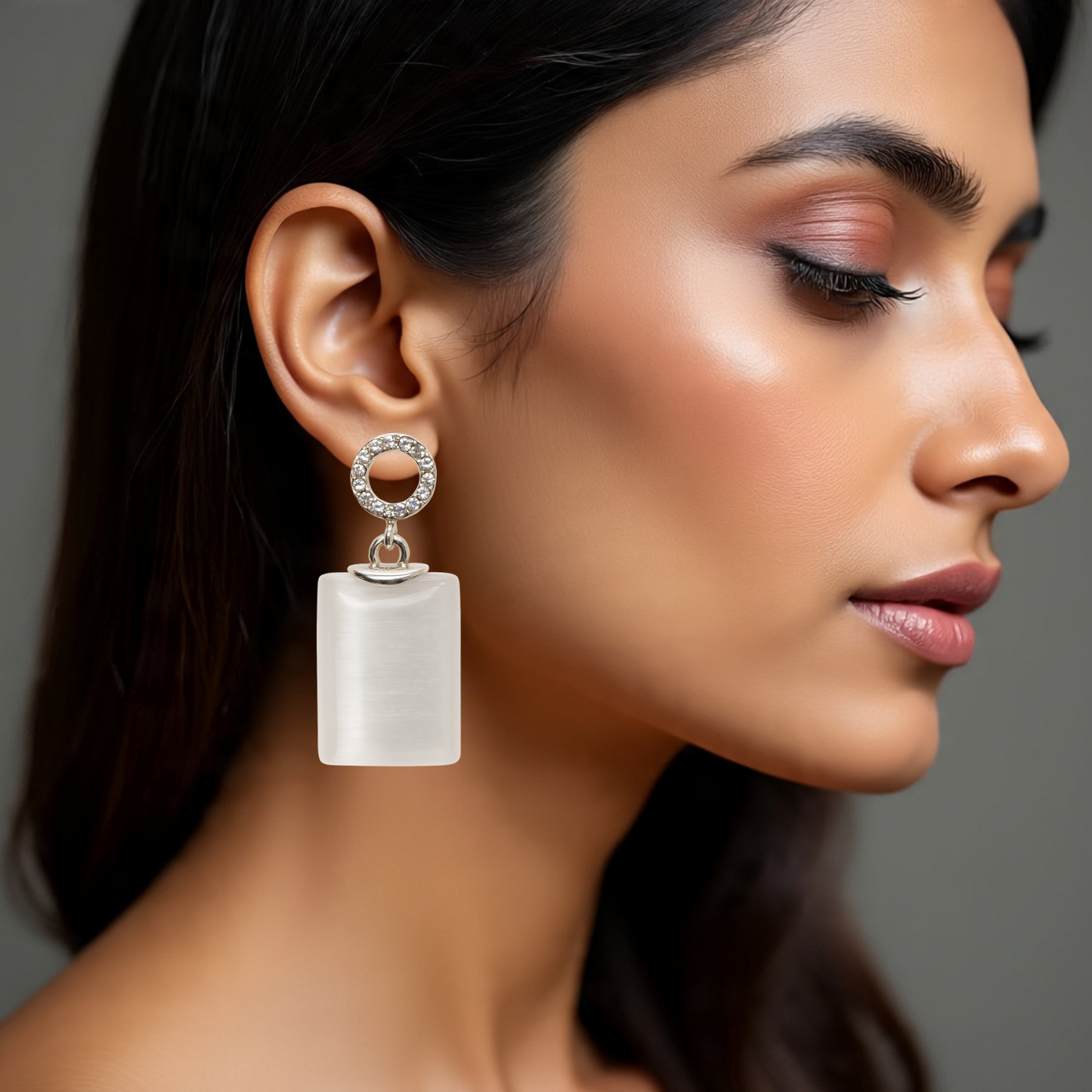 Close-up of a woman wearing a unique earring with a gray background