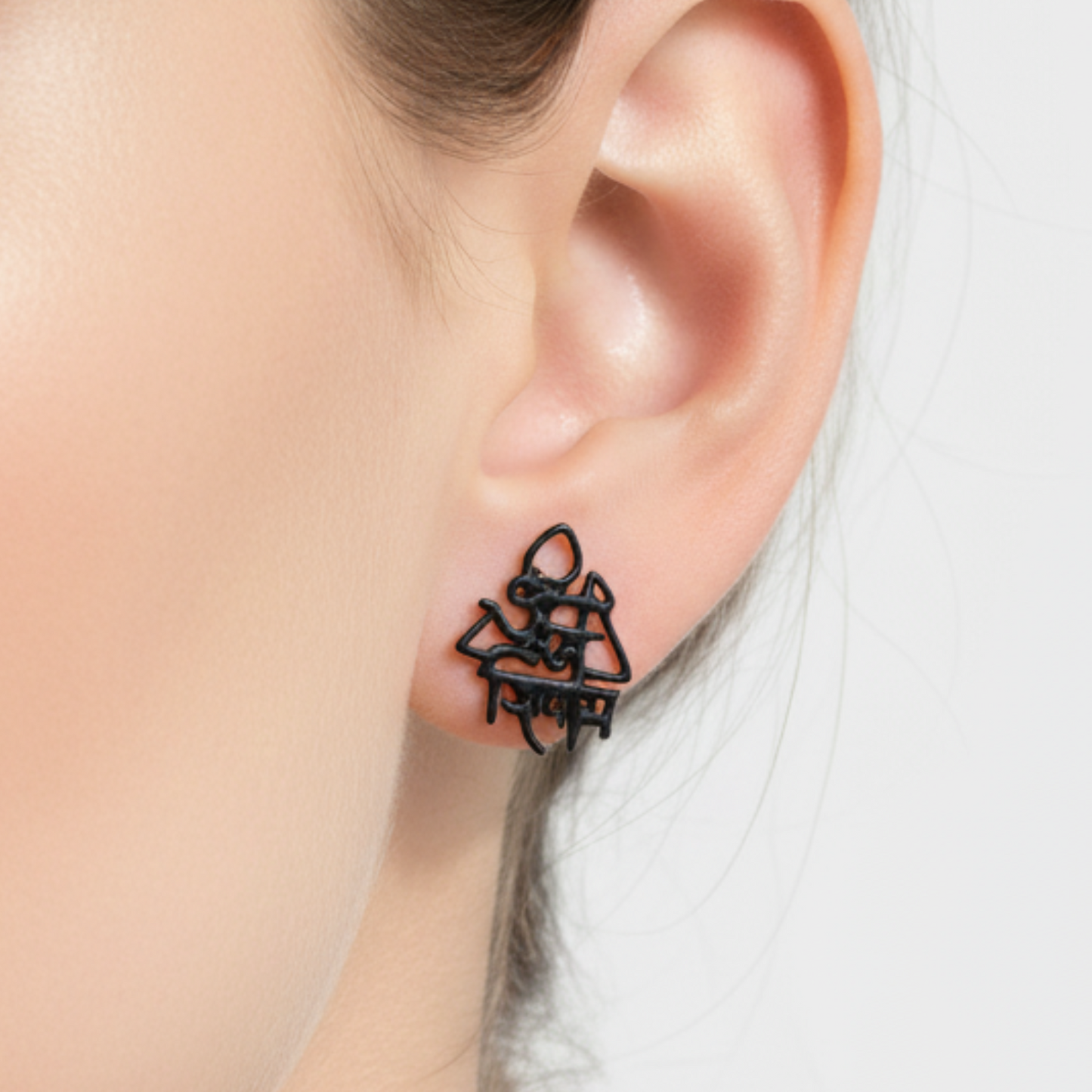 Black earrings worn by a person with a neutral background