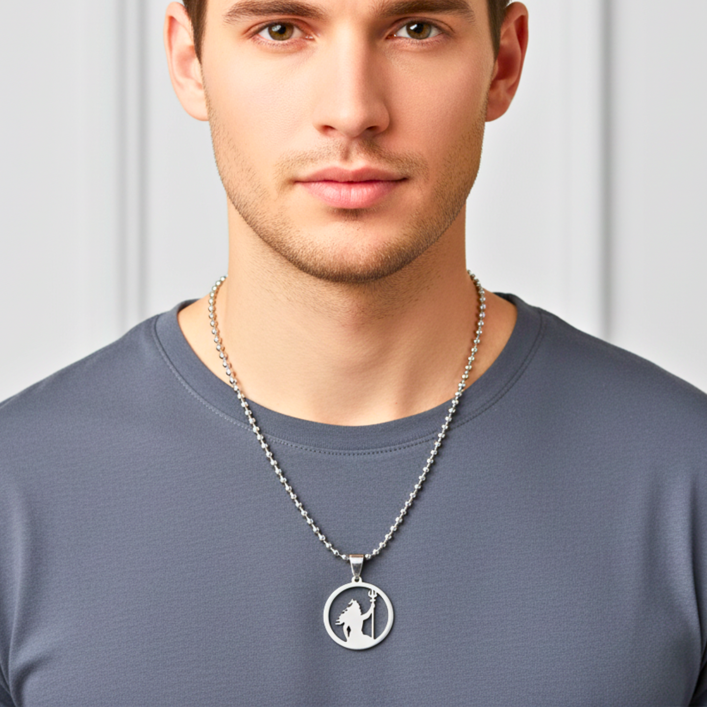Man wearing a silver necklace with a pendant on a plain background