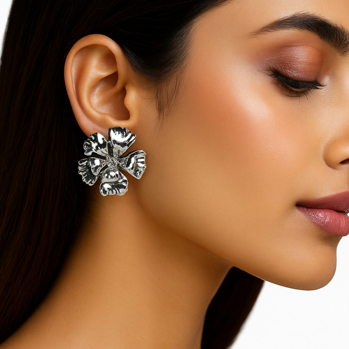 Close-up of a woman wearing a silver floral earring on a white background
