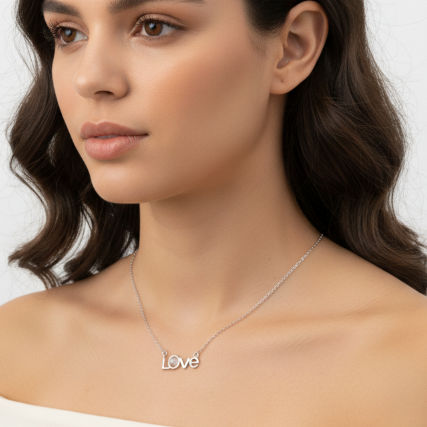 Woman wearing a 'Love' necklace on a neutral background