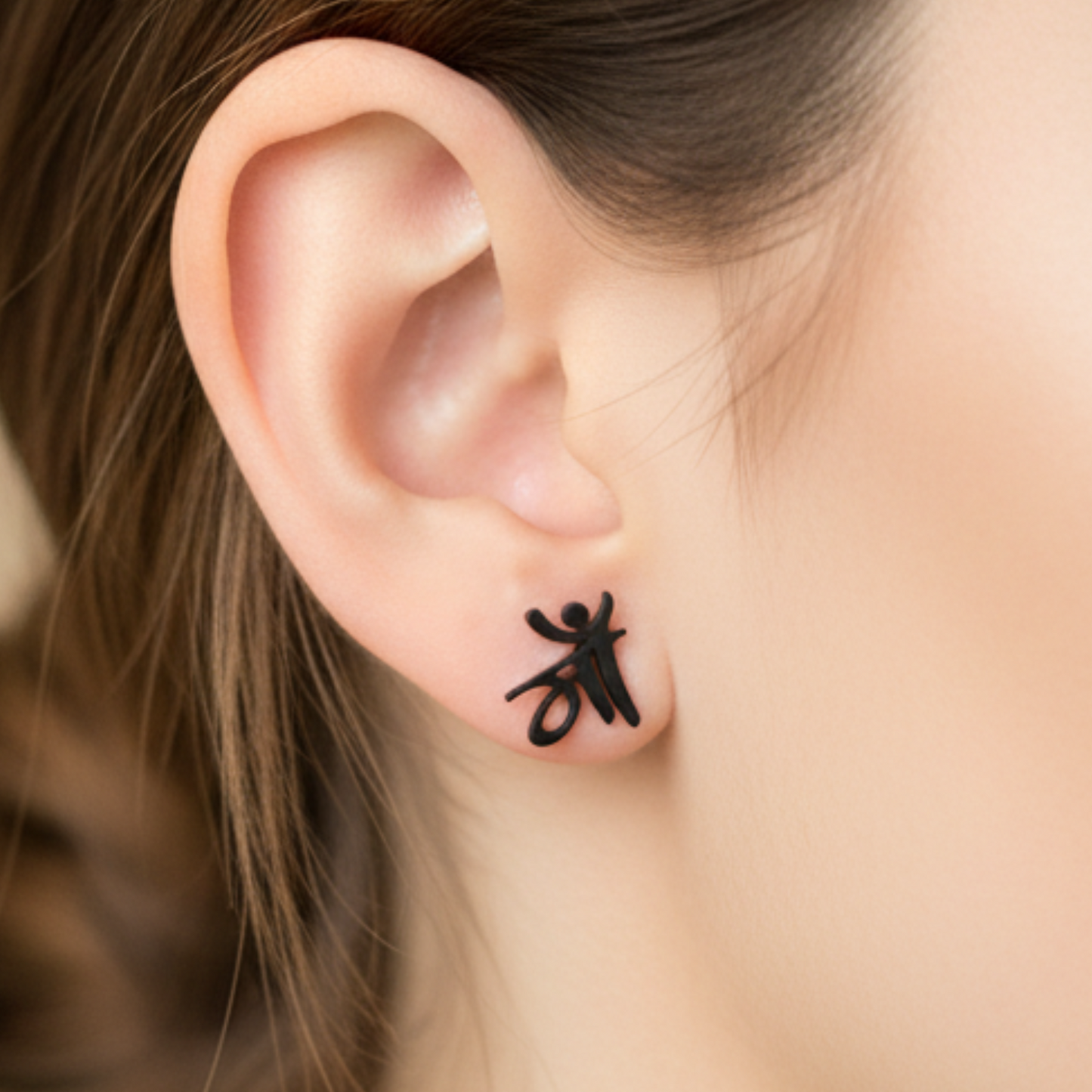 Close-up of an ear with a black insect-shaped earring on a blurred background