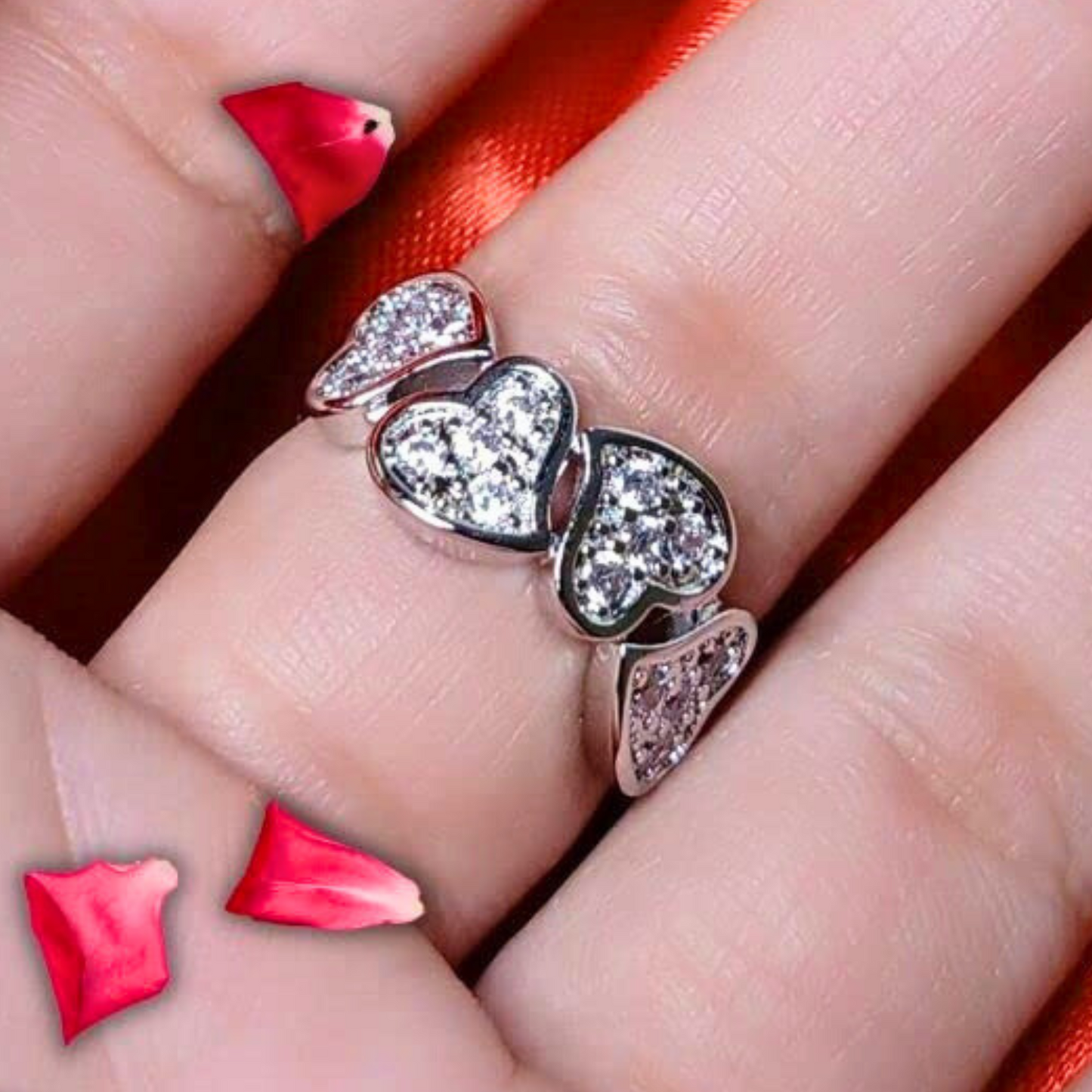 Heart-shaped ring on a finger with red heart decorations.