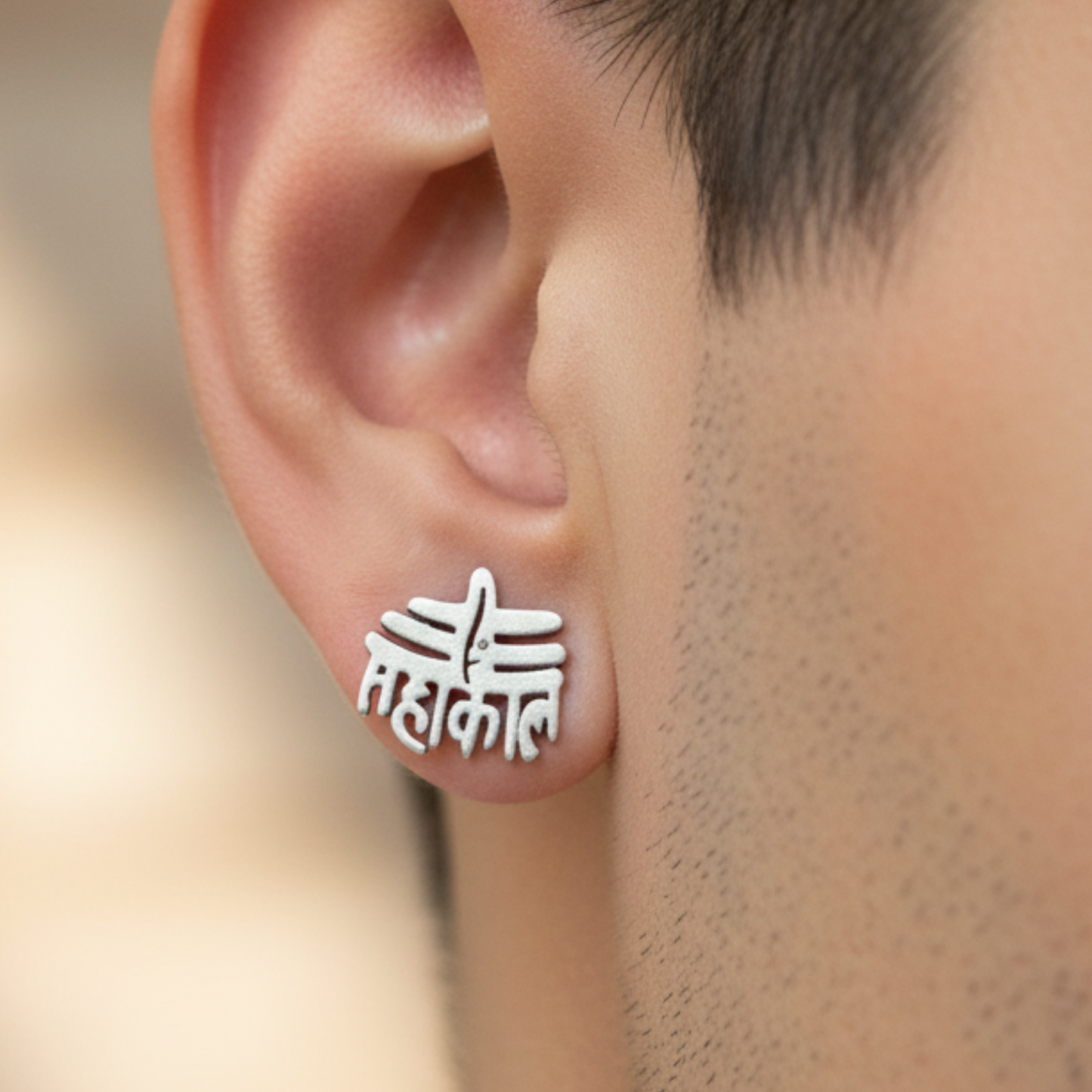 Silver stud earrings worn on an ear with a blurred background