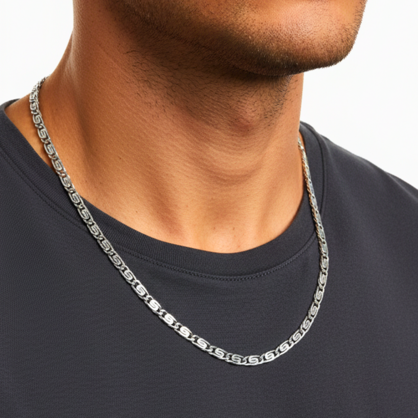 Silver chain necklace worn by a person on a plain background
