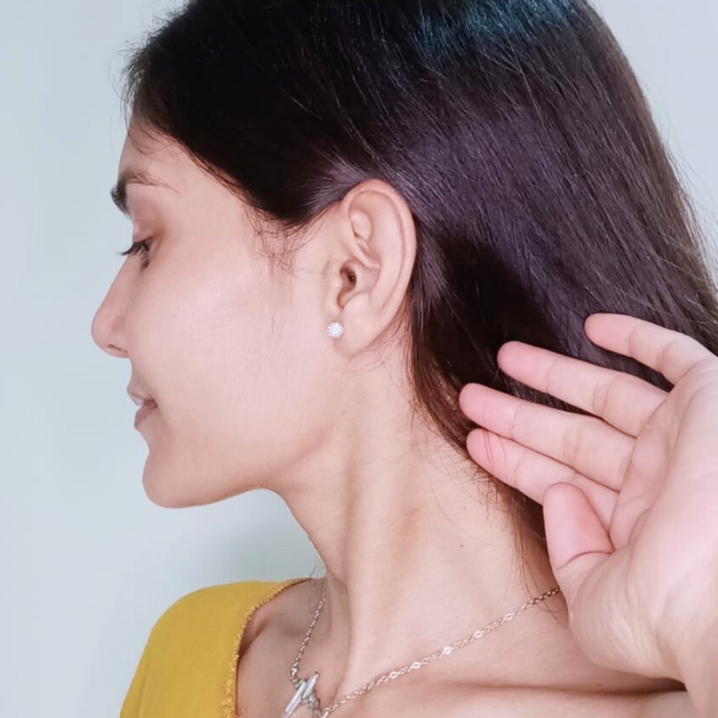 Woman wearing a pearl earring with a plain background
