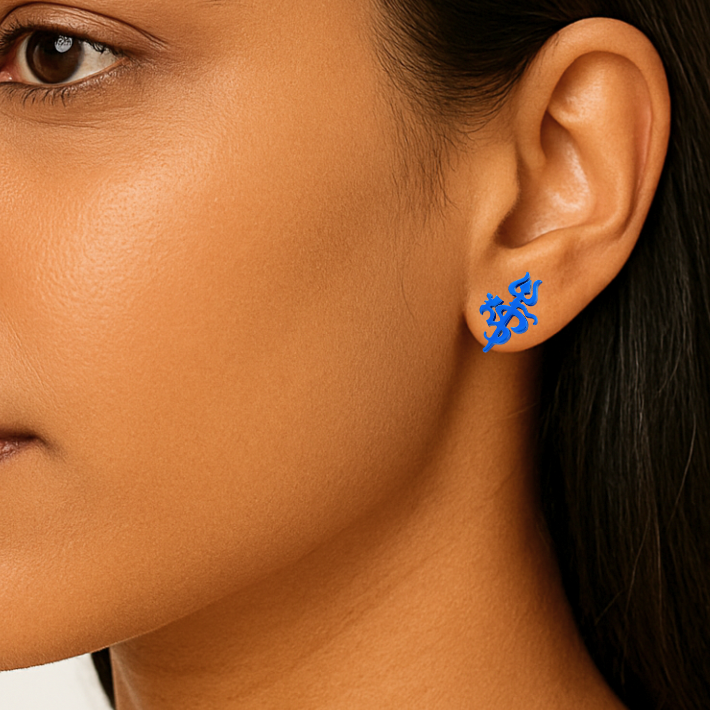Close-up of an ear wearing a blue earring with a stylized om design.