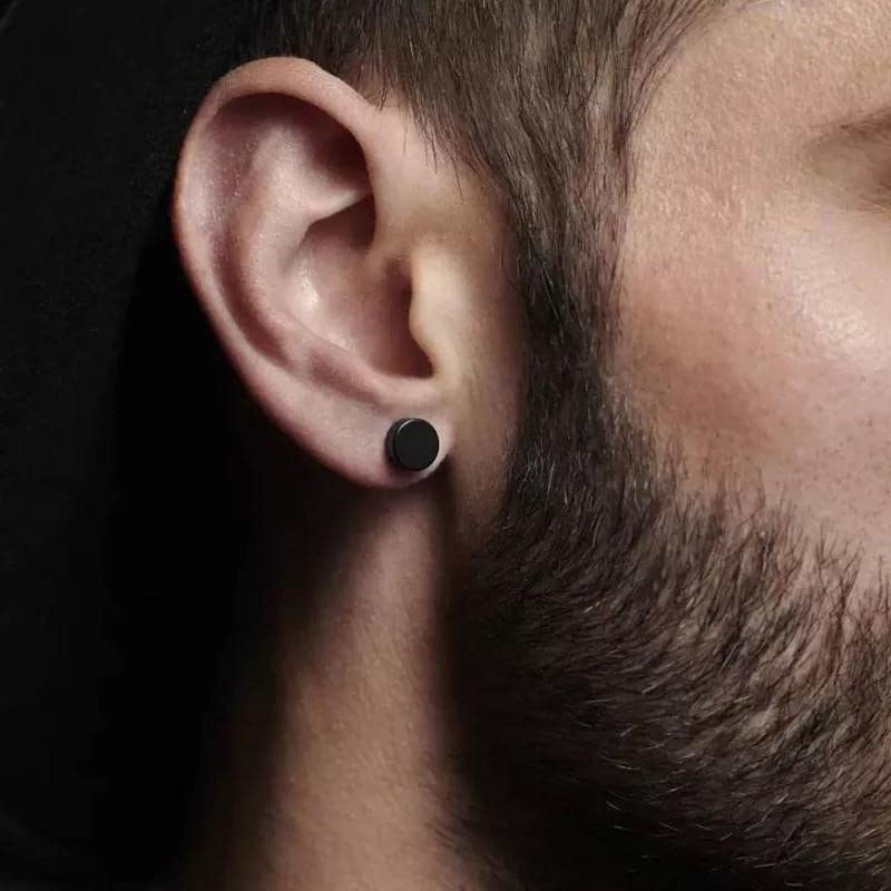 Close-up of a man's ear wearing a black stud earring.