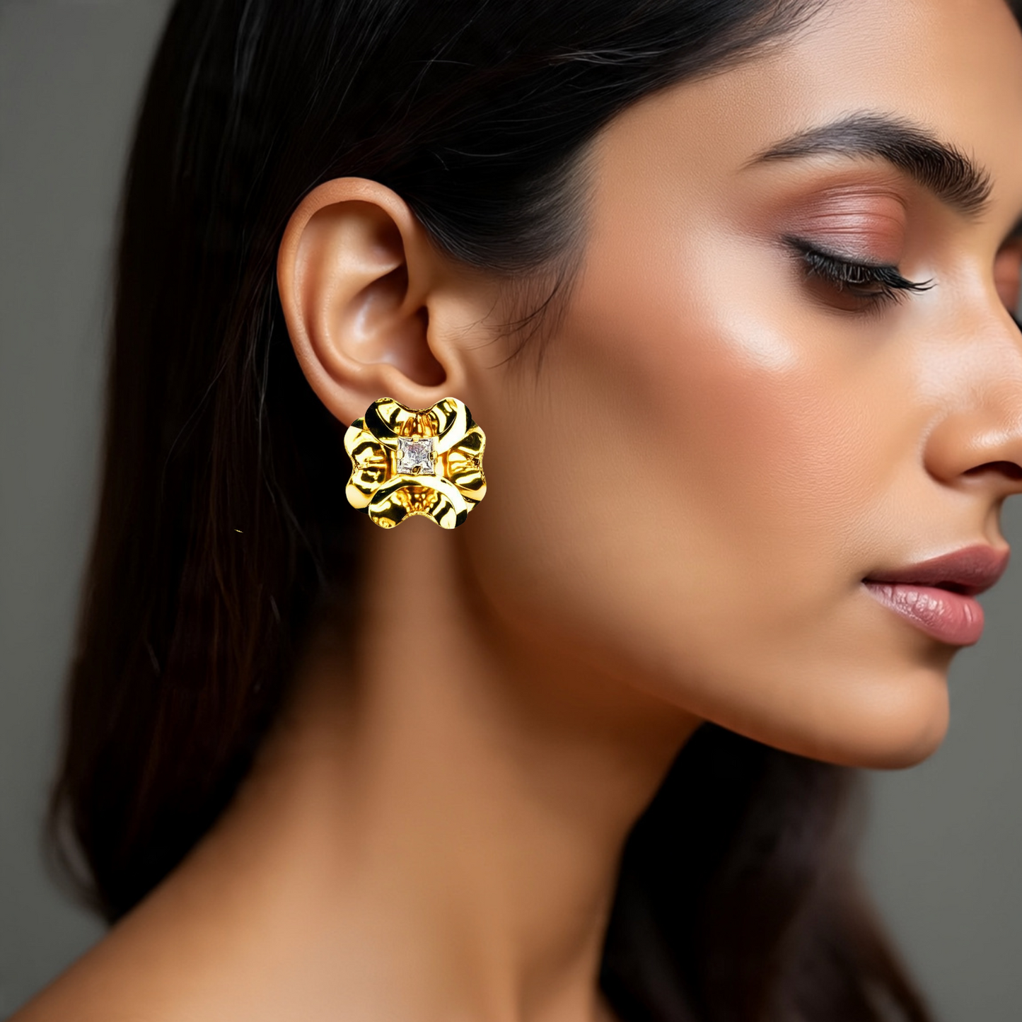 Close-up of a woman wearing gold earrings with a gray background