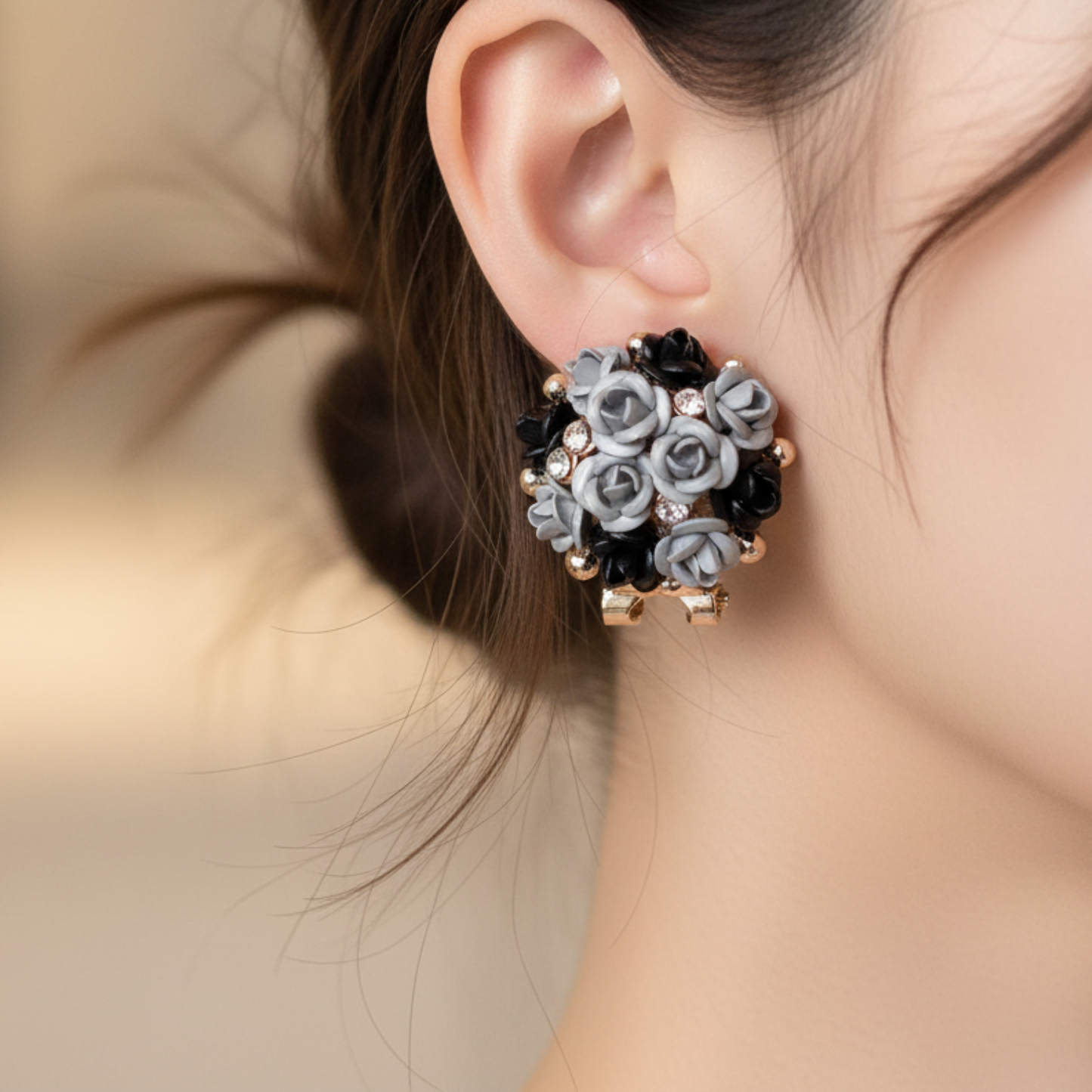 Close-up of an ear wearing a floral earring with black and gray flowers.