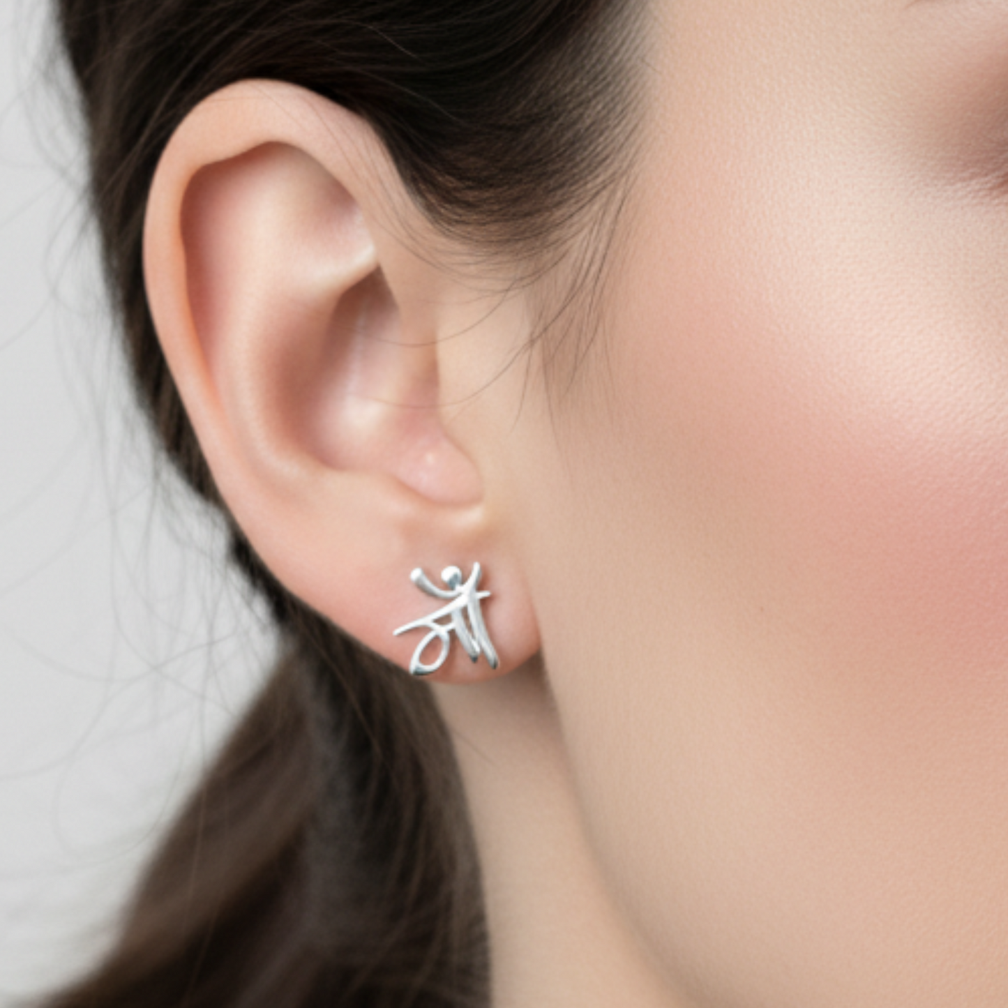 Silver earring worn by a person with a neutral background