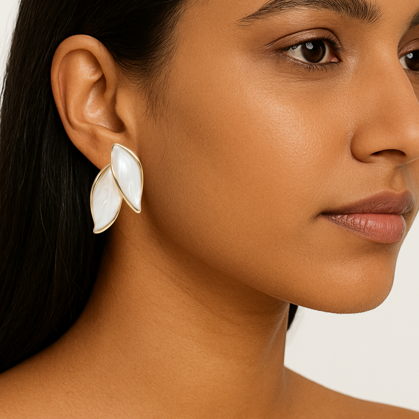 Close-up of a woman wearing a white floral earring on a neutral background
