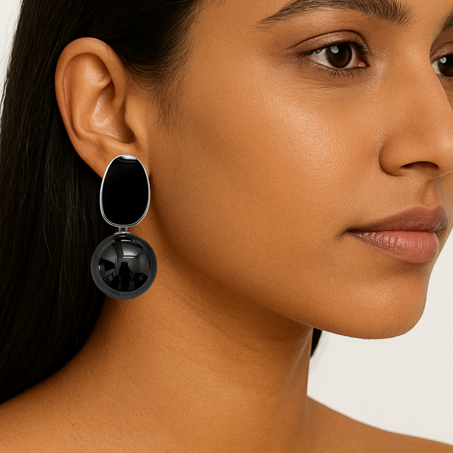 Close-up of a woman wearing black earrings with a neutral background