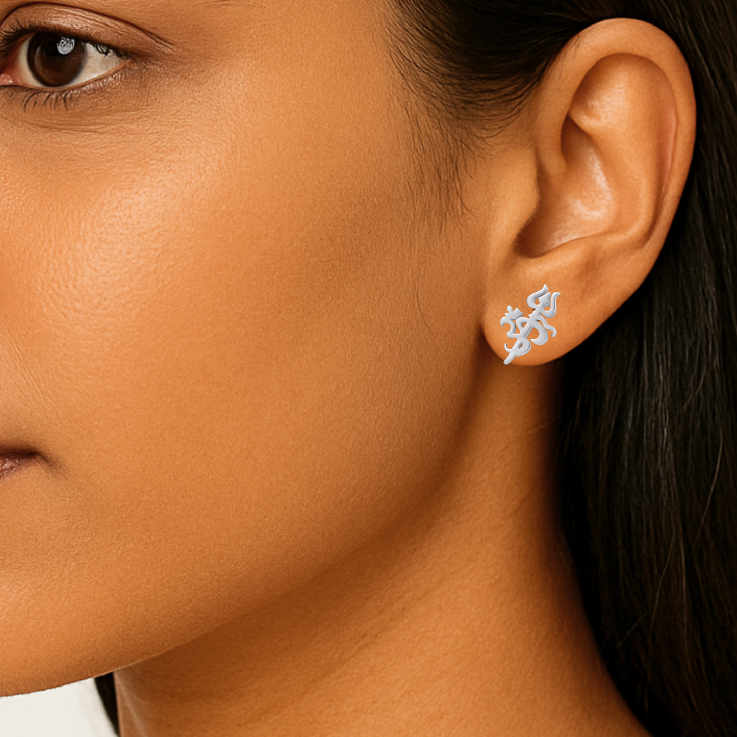 Close-up of a person wearing silver earrings with a geometric om design.