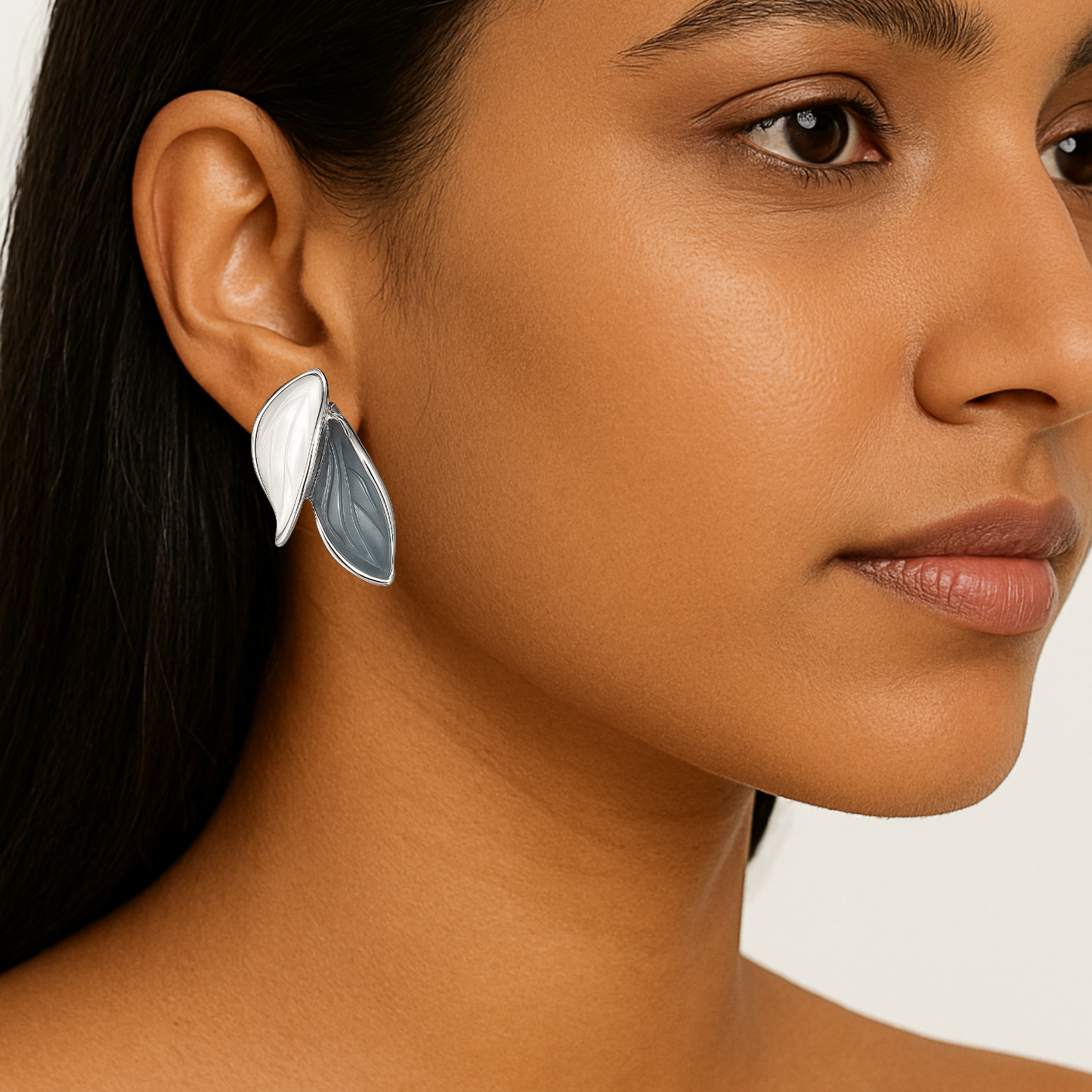 Close-up of a woman wearing a silver leaf-shaped earring on a white background