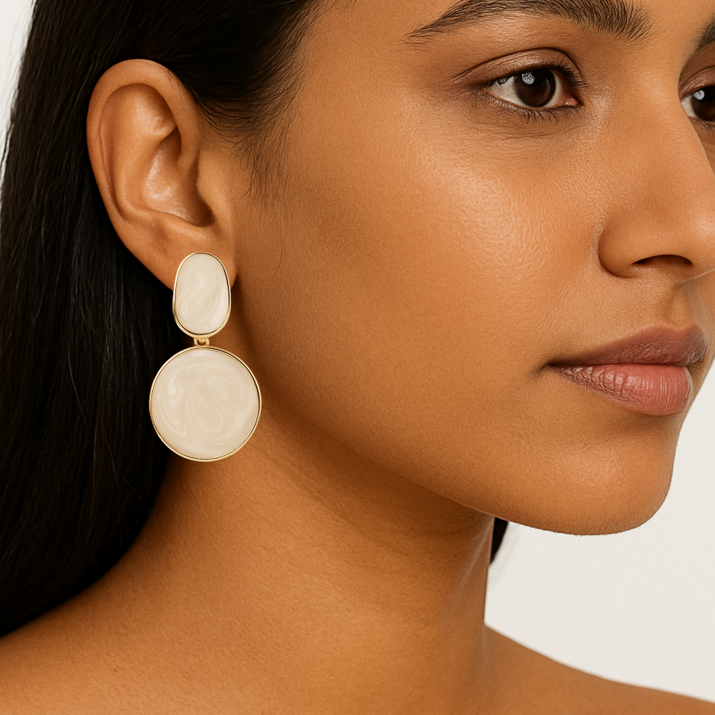Close-up of a woman wearing beige earrings with a neutral background