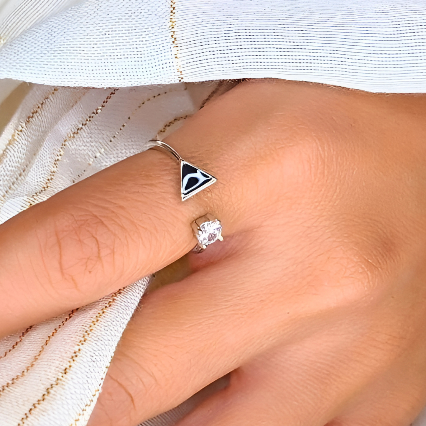 Close-up of a hand wearing two rings on a white fabric background
