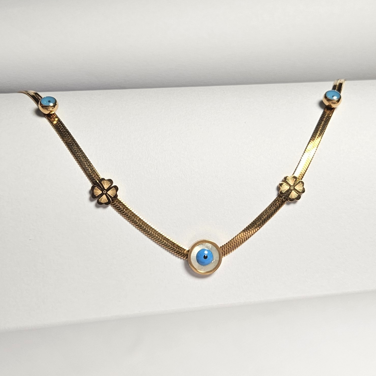 Gold necklace with blue eye charms on a white background