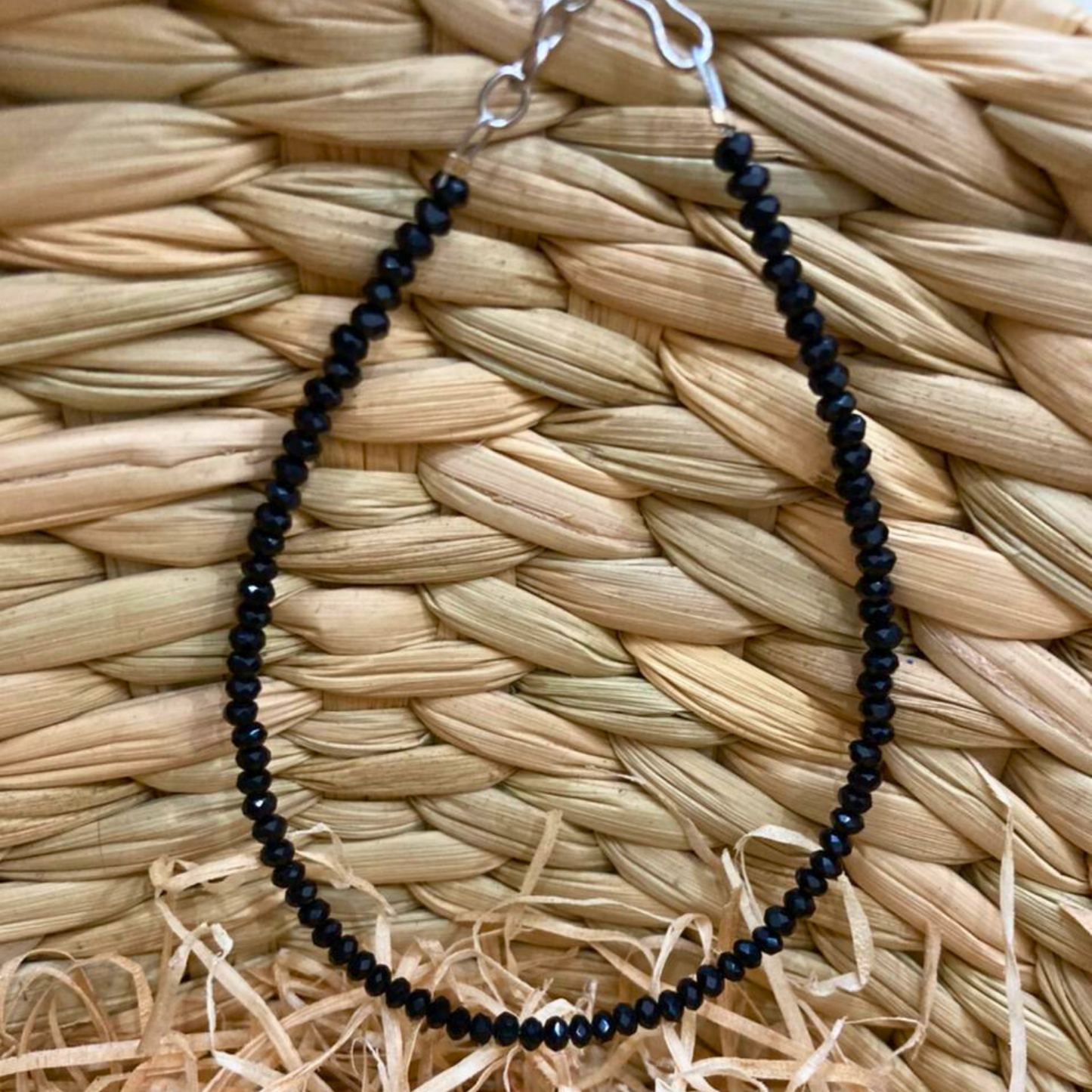 Black beaded necklace on a woven mat