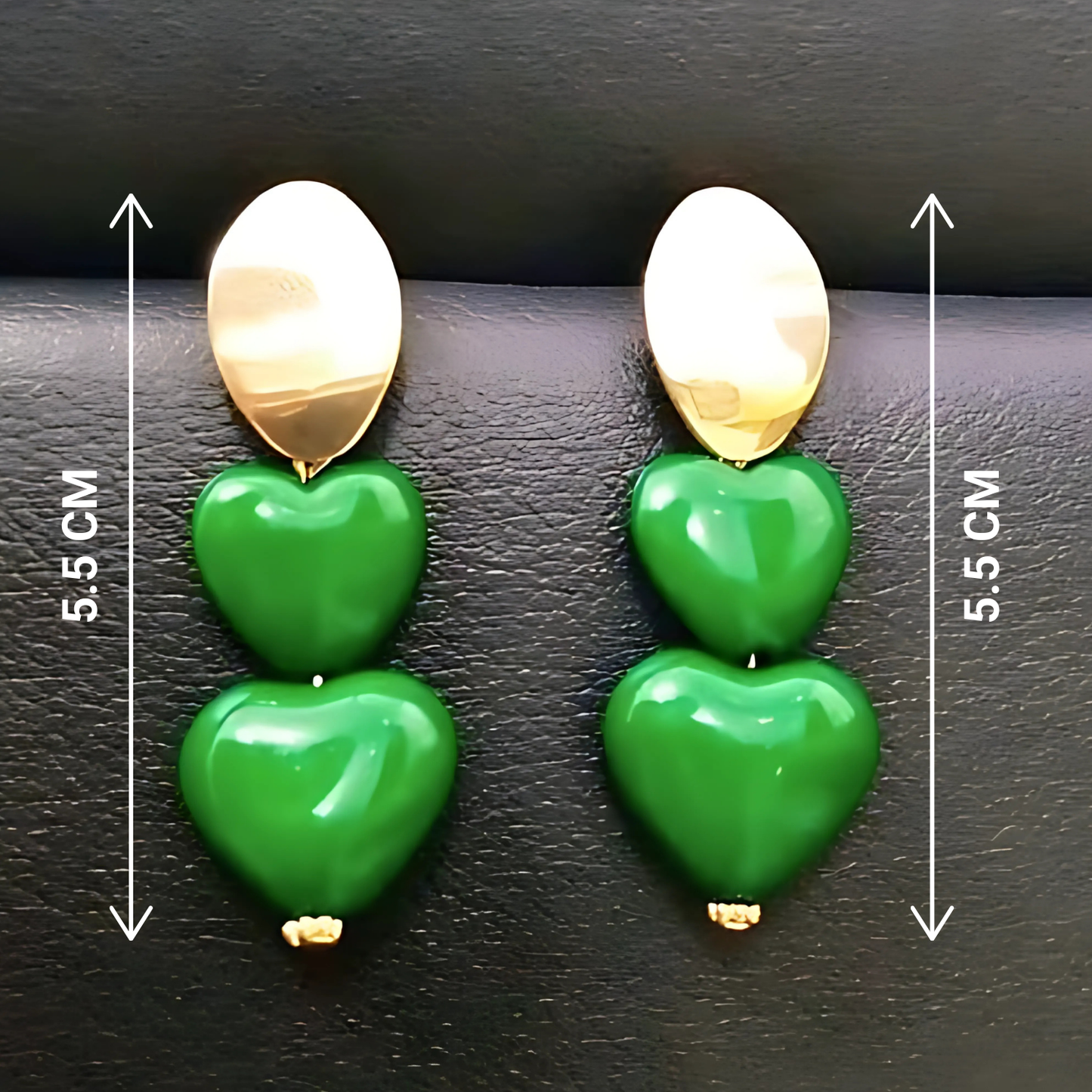 Green heart-shaped earrings with gold accents on a dark surface, showing measurements.