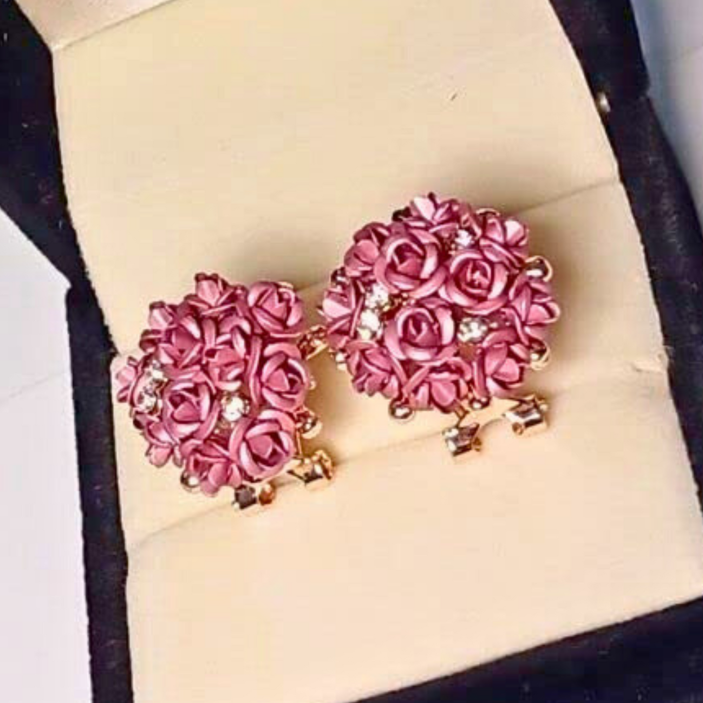 Pink rose-shaped earrings on a beige jewelry box
