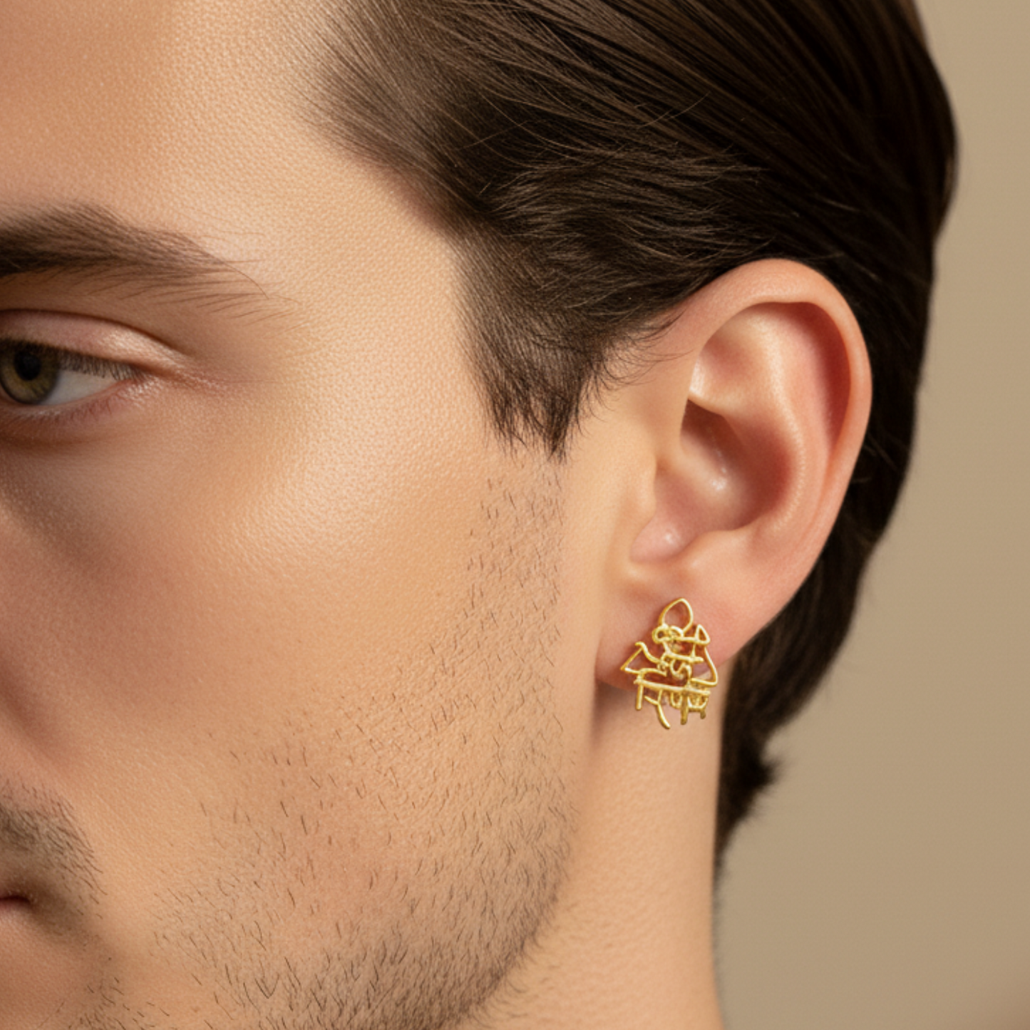 Gold earring worn by a person on a beige background