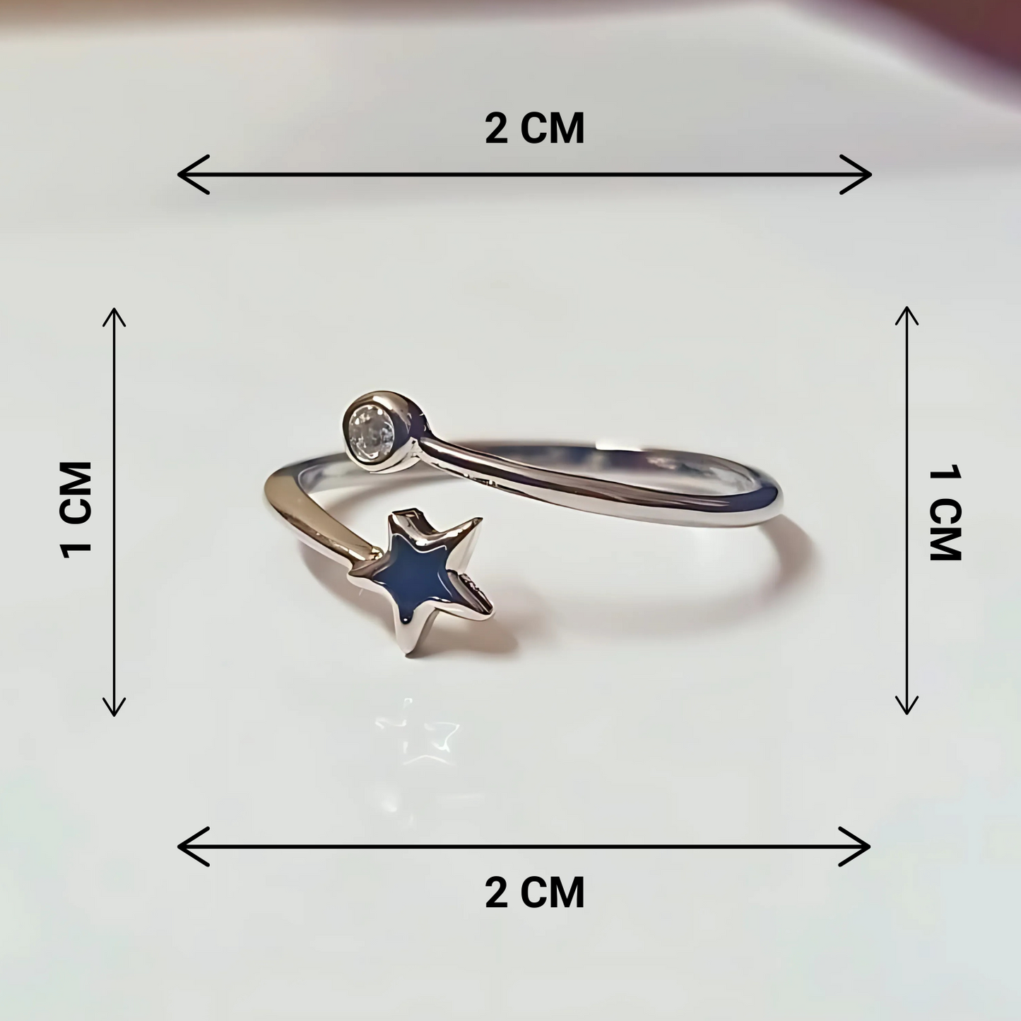 Silver ring with a black star charm and measurements on a white background