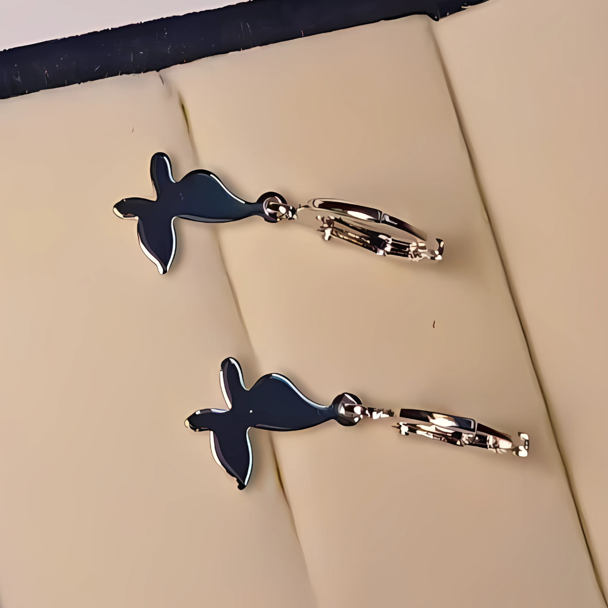 Pair of silver and silver earrings on a beige surface
